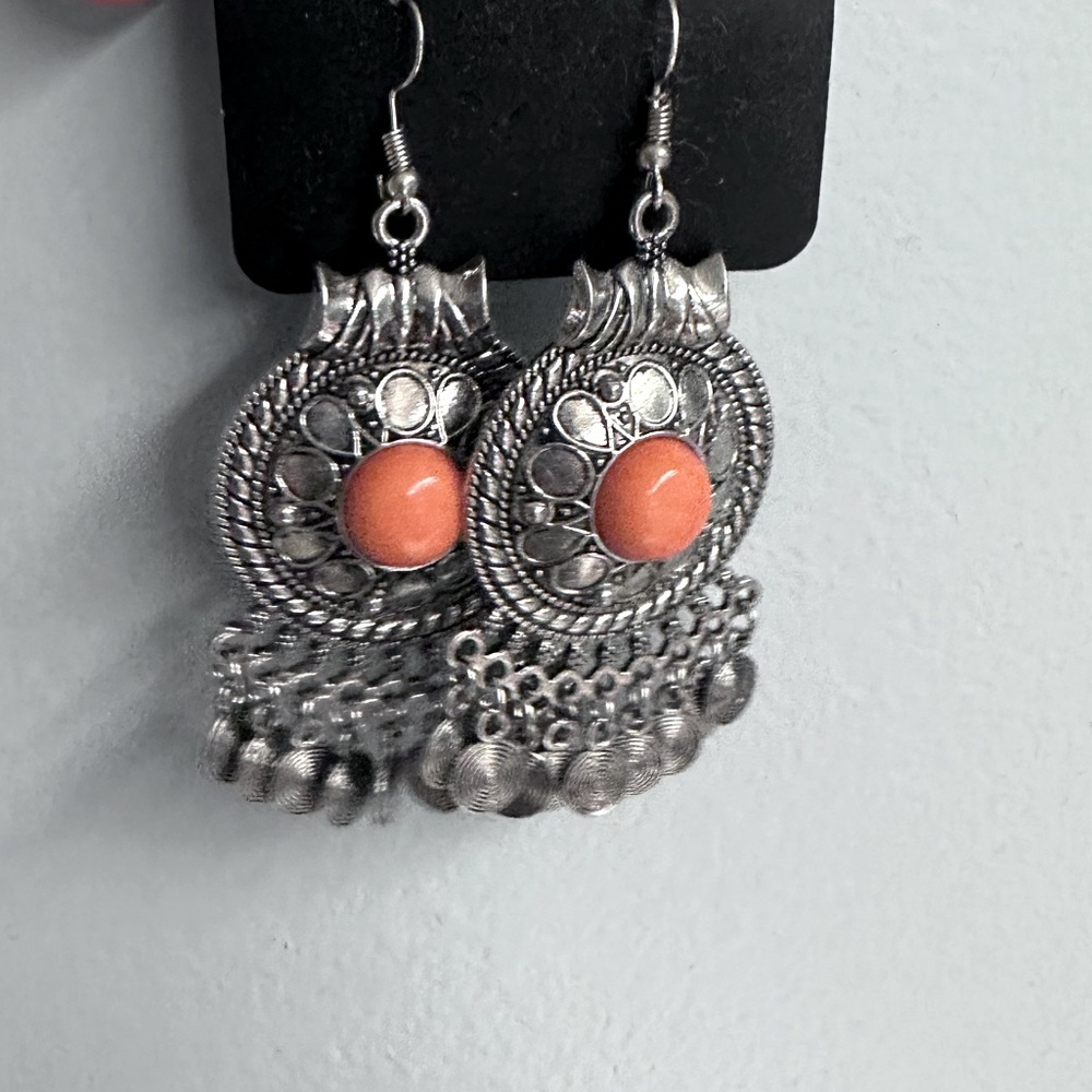 Silver earrings with orange middle accent.